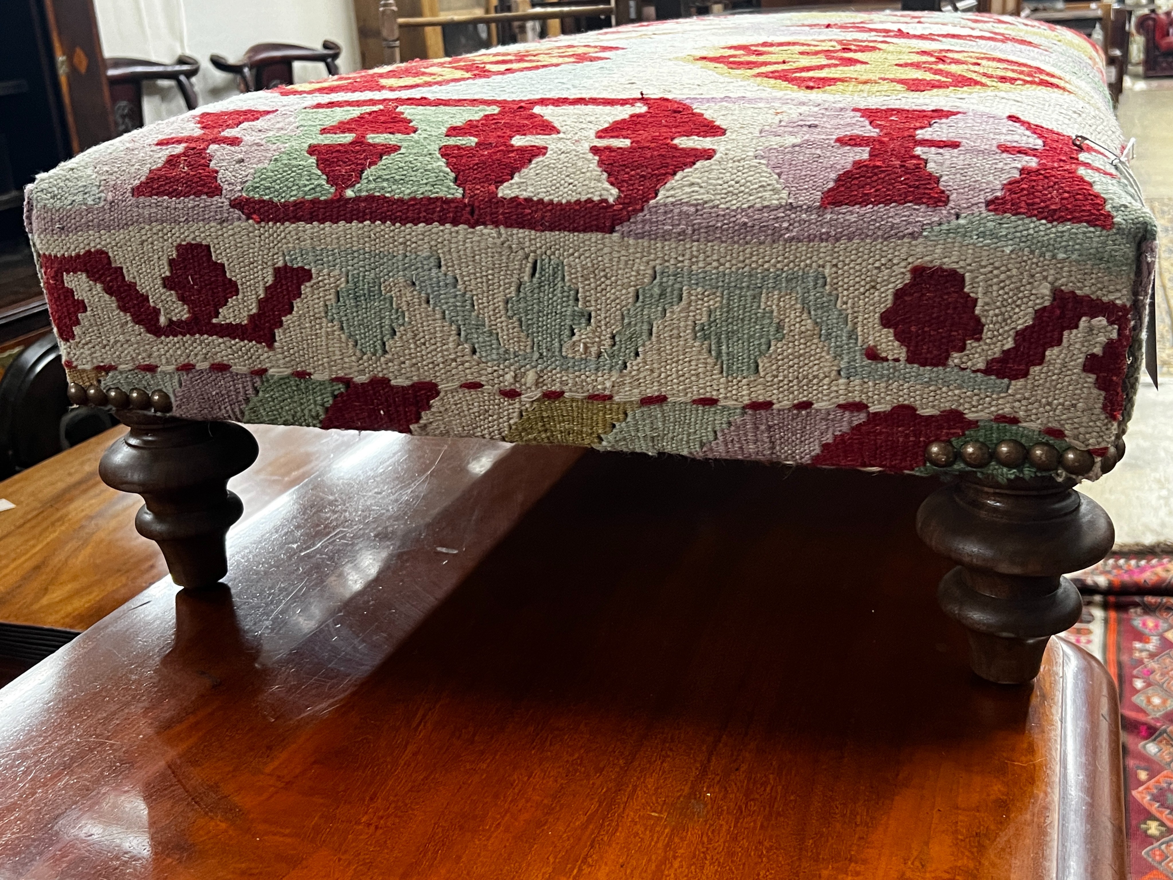 A large contemporary rectangular polychrome Kilim footstool on turned feet, length 108cm, depth 64cm, height 30cm